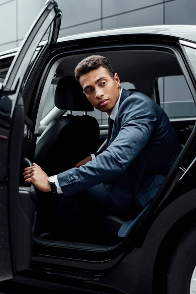 Hombre de negocios afroamericano en traje abriendo la puerta del coche - foto de stock