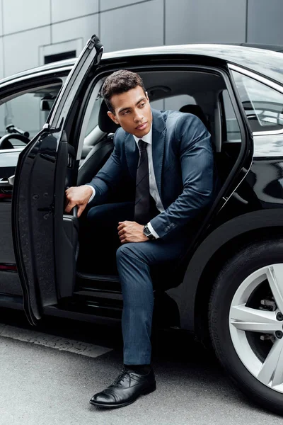 African american man in suit opening black car door — Stock Photo