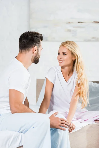 Beau couple en pyjama se regardant sur le lit à la maison — Photo de stock