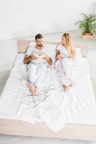 High Angle View of couple in pajamas relaxing in bed with books at home — Stock Photo