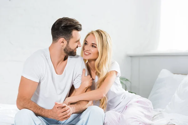 Beau sourire couple câlin sur lit à la maison — Photo de stock