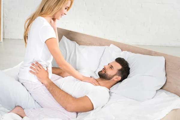 Beautiful couple in pajamas hugging in bed at home — Stock Photo