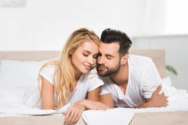 Beautiful couple with eyes closed resting on bed at home — Stock Photo