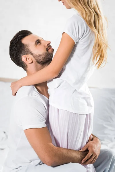 Belo jovem casal abraçando na cama em casa — Fotografia de Stock