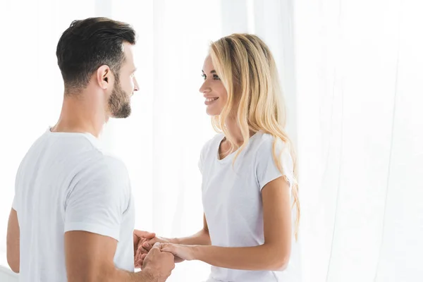 Beautiful happy couple in pajamas holding hands at home — Stock Photo