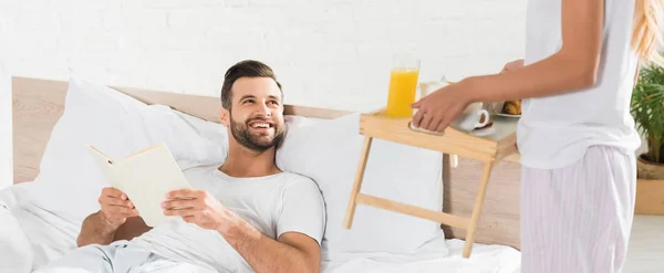 Colpo panoramico di donna che porta la colazione all'uomo a letto al mattino — Foto stock