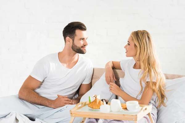 Beautiful couple in pajamas having breakfast in bed in morning — Stock Photo