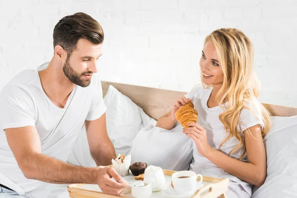 Hermosa pareja desayunando en la cama por la mañana - foto de stock