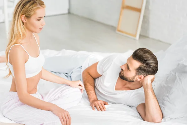 Belle femme assise sur le lit près de bel homme à la maison — Photo de stock