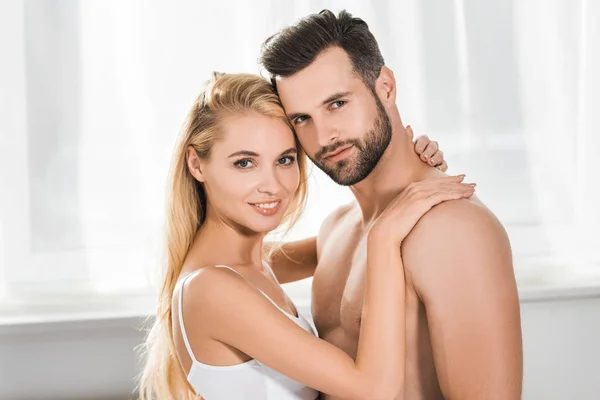 Schönes romantisches Paar blickt in die Kamera, während es sich zu Hause umarmt — Stockfoto