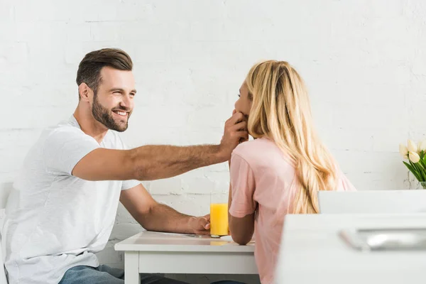 Beautiful couple having breakfast at kitchen table in morning — Stock Photo