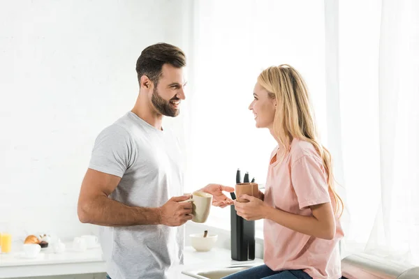 Belo casal com xícaras de café durante o café da manhã na cozinha — Fotografia de Stock