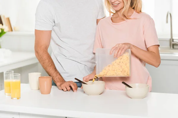 Cropped view of woman pouring cereal during breakfast near man at kitchen — Stock Photo