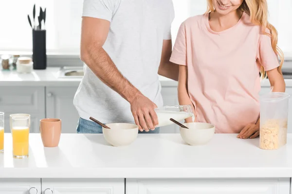 Vista cortada de casal com tigelas de cereais durante o café da manhã na cozinha — Fotografia de Stock