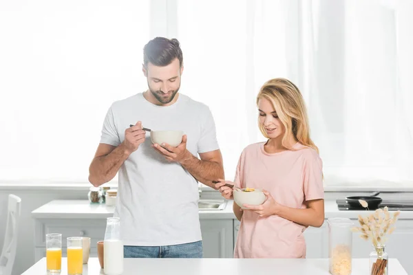 Pareja feliz comer cereales durante el desayuno en la cocina - foto de stock