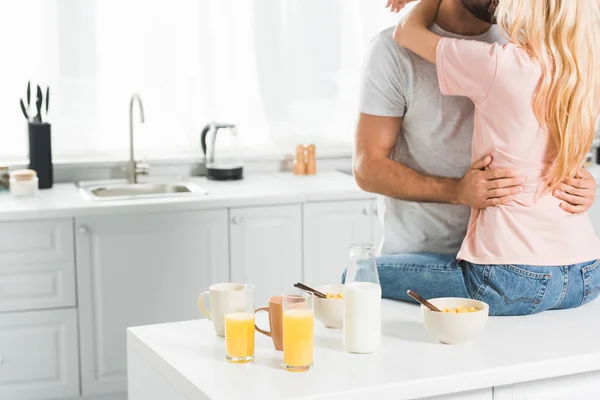 Vista ritagliata di coppia che si abbraccia sul bancone della cucina durante la colazione in cucina — Foto stock