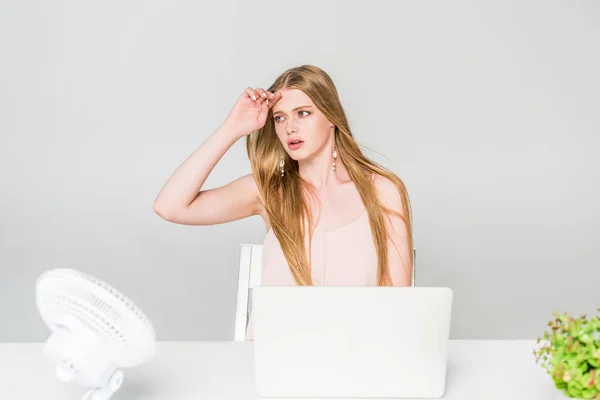 Fille souffrant de chaleur avec ventilateur électrique au bureau de l'ordinateur sur gris — Photo de stock