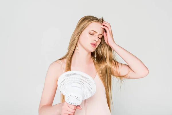 Young woman suffering from heat and holding Electric Fan isolated on grey — Stock Photo