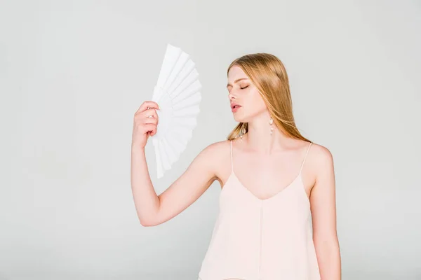 Bella giovane donna con ventilatore a mano che soffre di calore sul grigio — Foto stock