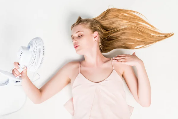 Top view of girl holding Electric Fan while suffering from heat on white — стоковое фото