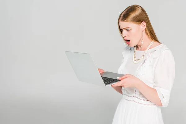 Shocked girl using laptop on grey with copy space — Stock Photo