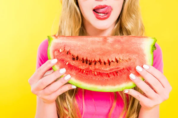 Abgeschnittene Ansicht des Mädchens, das die Zunge herausstreckt und Wassermelone isoliert auf gelb hält — Stockfoto