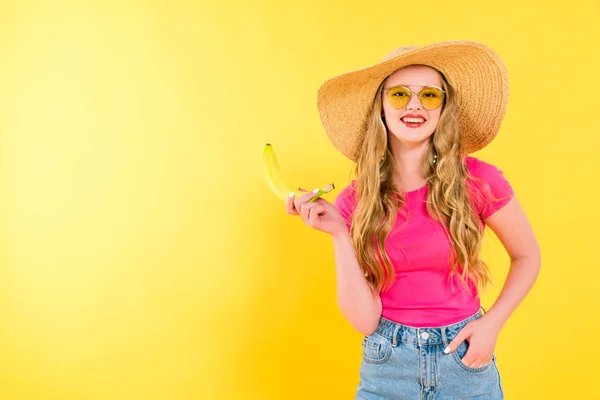 Красива усміхнена дівчина в солом'яному капелюсі з бананом На жовтому — стокове фото