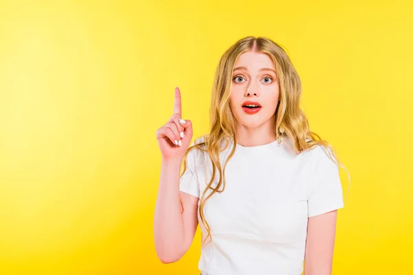 Confusa bionda giovane donna che punta con il dito isolato sul giallo — Foto stock