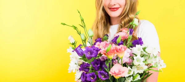 Plano panorámico de chica rubia con flores aisladas en amarillo - foto de stock