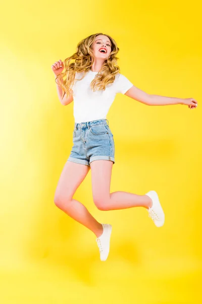 Красива щаслива блондинка молода жінка стрибає на жовтому — стокове фото