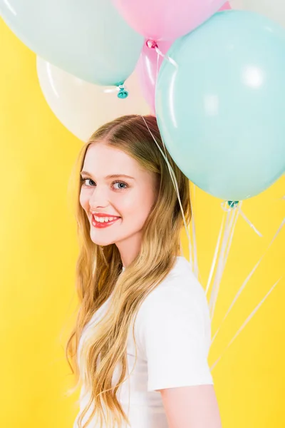 Bela menina feliz com balões isolados em amarelo — Fotografia de Stock