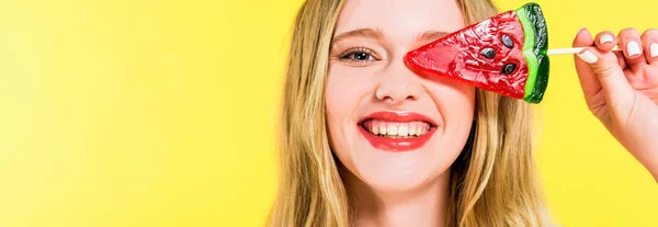 Colpo panoramico di bella ragazza sorridente con lecca-lecca a forma di anguria isolato su giallo — Foto stock