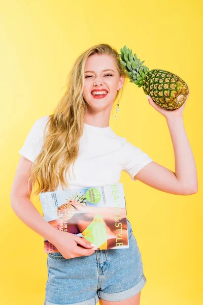 Schönes Mädchen mit Schönheits- und Stilmagazin und Ananas auf Gelb — Stockfoto