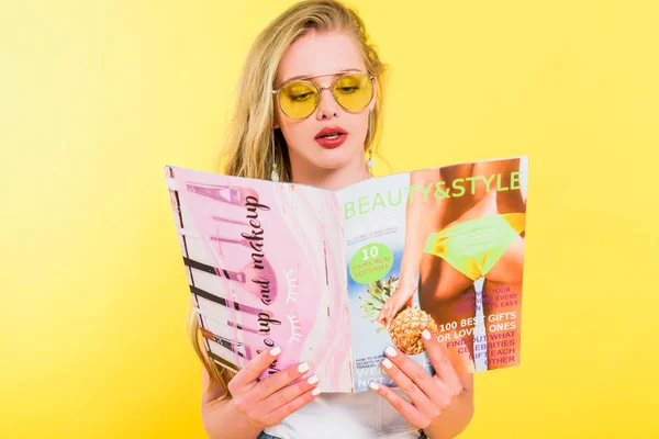 Beautiful girl reading beauty and style magazine On yellow — Stock Photo