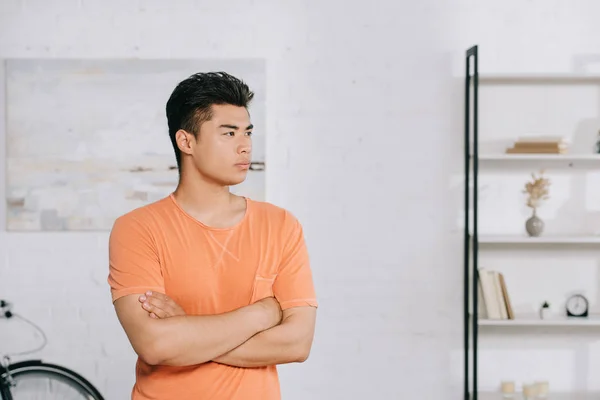 Serious asian man standing with crossed arms and looking away in kitchen — Stock Photo