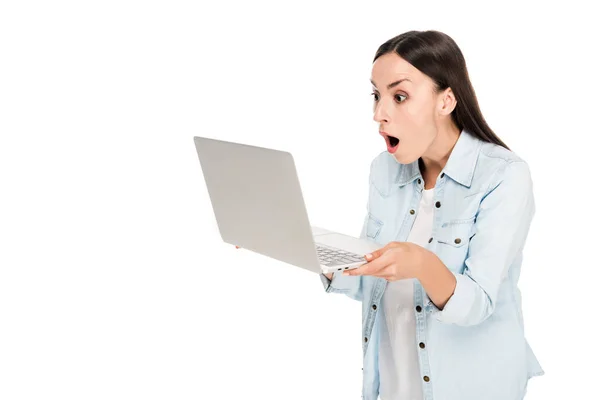 Shocked girl in denim jacket using laptop isolated on white — Stock Photo