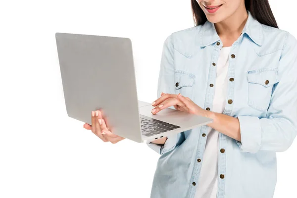 Partial view of smiling girl in denim jacket using laptop isolated on white — Stock Photo