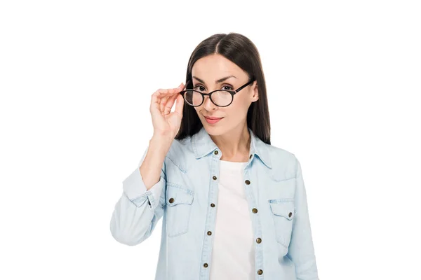 Curiosa ragazza bruna in occhiali e giacca di jeans guardando la fotocamera isolata sul bianco — Foto stock