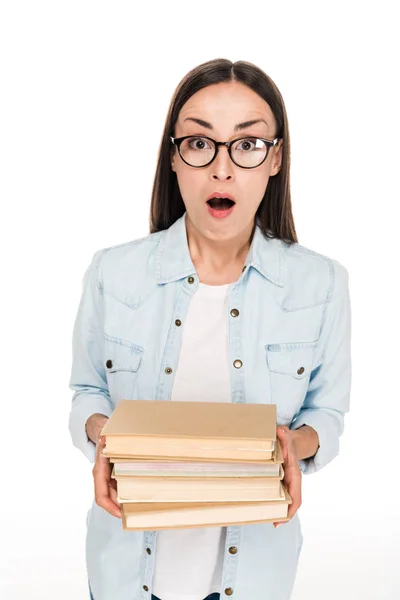 Shocked brunette girl in glasses and denim jacket holding books isolated on white — Stock Photo