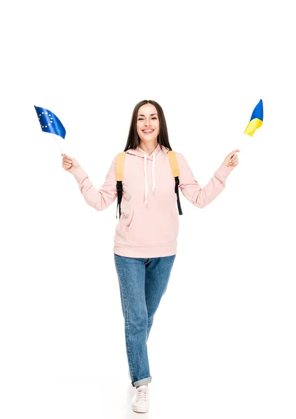 Visão de comprimento total do estudante sorridente com mochila segurando bandeiras ucranianas e europeias isoladas em branco — Fotografia de Stock