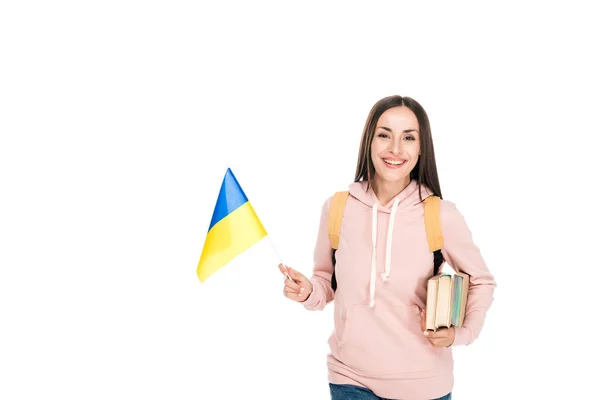 Estudiante sonriente con mochila sosteniendo bandera ucraniana y libros aislados en blanco - foto de stock