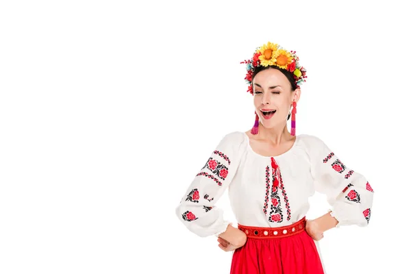 Brünette junge Frau in ukrainischer Nationaltracht mit den Händen auf den Hüften, die vereinzelt auf weiß zwinkern — Stockfoto