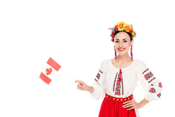 Morena joven en traje nacional ucraniano sosteniendo bandera de Canadá aislado en blanco - foto de stock