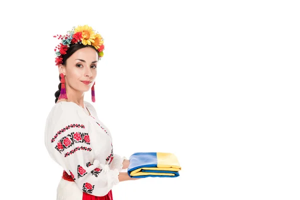 Vista lateral de mujer joven morena en traje nacional ucraniano sosteniendo bandera aislada en blanco - foto de stock