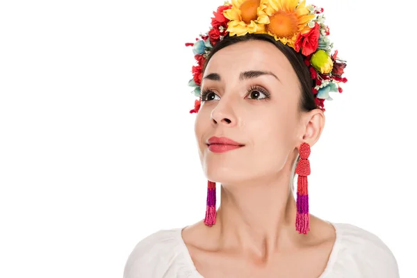 Morena mujer joven en camisa bordada ucraniana nacional y corona floral mirando hacia otro lado aislado en blanco - foto de stock