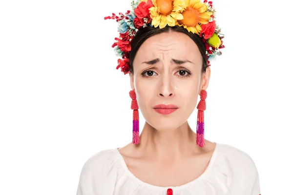 Upset brunette young woman in national Ukrainian embroidered shirt and floral wreath isolated on white — Stock Photo