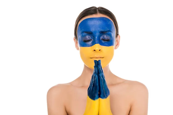 Naked young woman with painted Ukrainian flag on skin praying with closed eyes isolated on white — Stock Photo