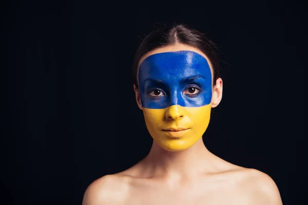 Jovem mulher nua com bandeira ucraniana pintada na pele olhando para a câmera isolada no preto — Fotografia de Stock