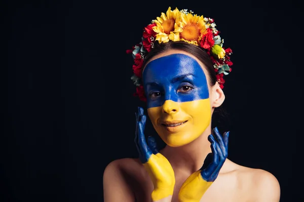 Heureux nu jeune femme en couronne florale avec peint drapeau ukrainien sur la peau hurlant isolé sur noir — Photo de stock