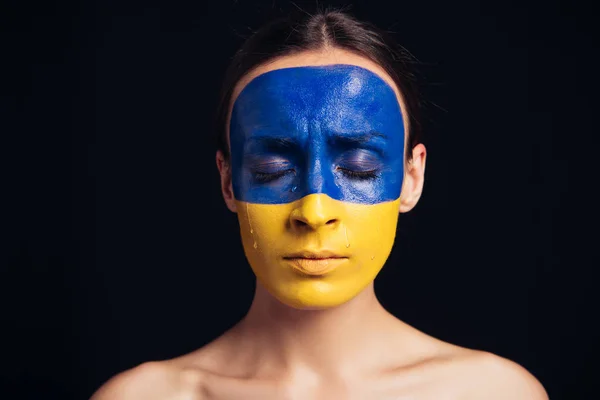 Гола молода жінка з розписом українського прапора на шкірі і закритими очима ізольовані на чорному — стокове фото